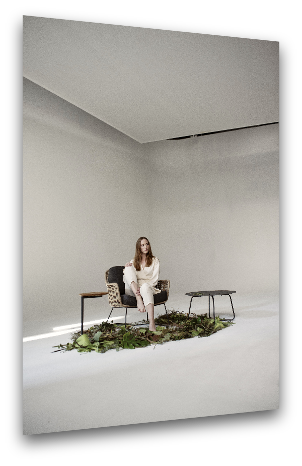 Person auf Korbstuhl in minimalistischem Setting mit grünem Boden im Mietstudio von Arts Unlimited 4 Rent