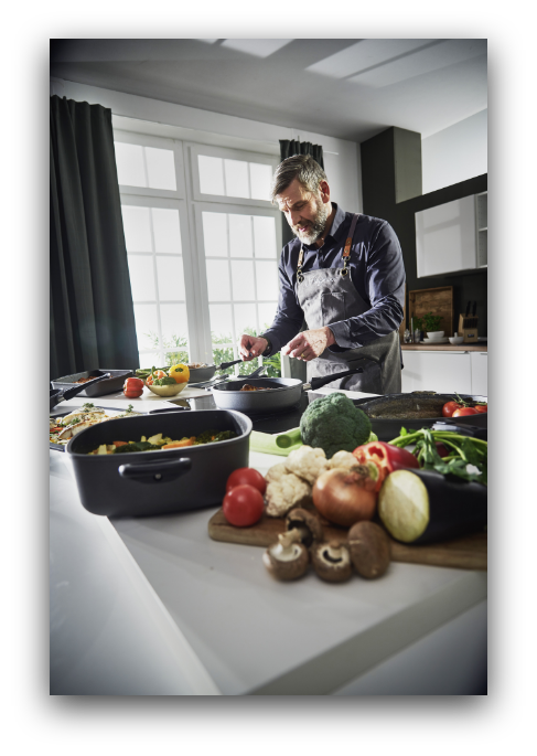 „Person beim Kochen im Studio von Arts Unlimited 4Rent mit frischem Gemüse und moderner Küchenausstattung“